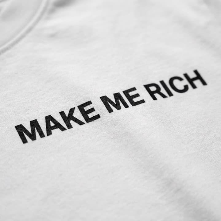 Close-up of the print: White t-shirt with a small MAKE ME RICH print on the chest and MAKE NO MISTAKES in huge black type across the back