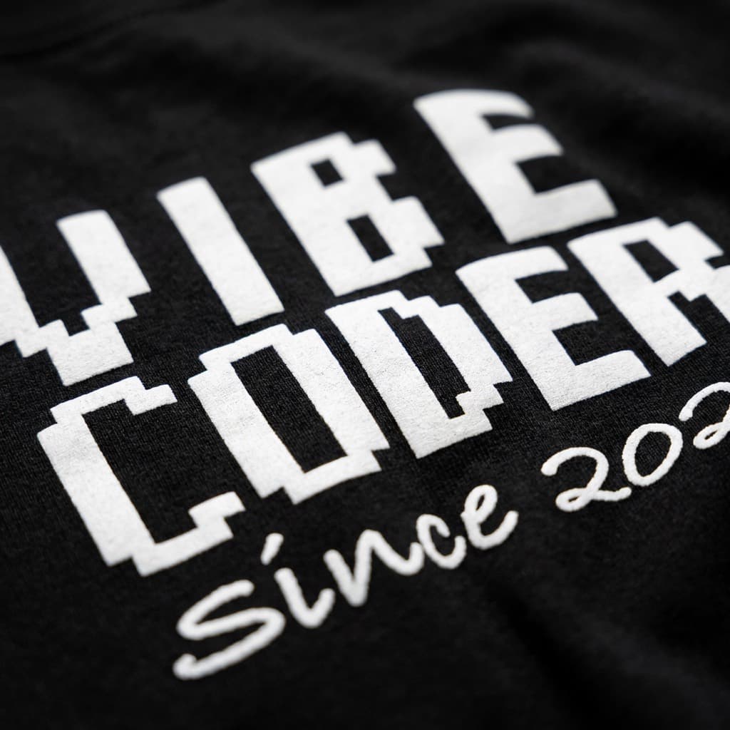 Close-up of the print: Black t-shirt with a small left-chest print reading VIBE CODER, Since 2025